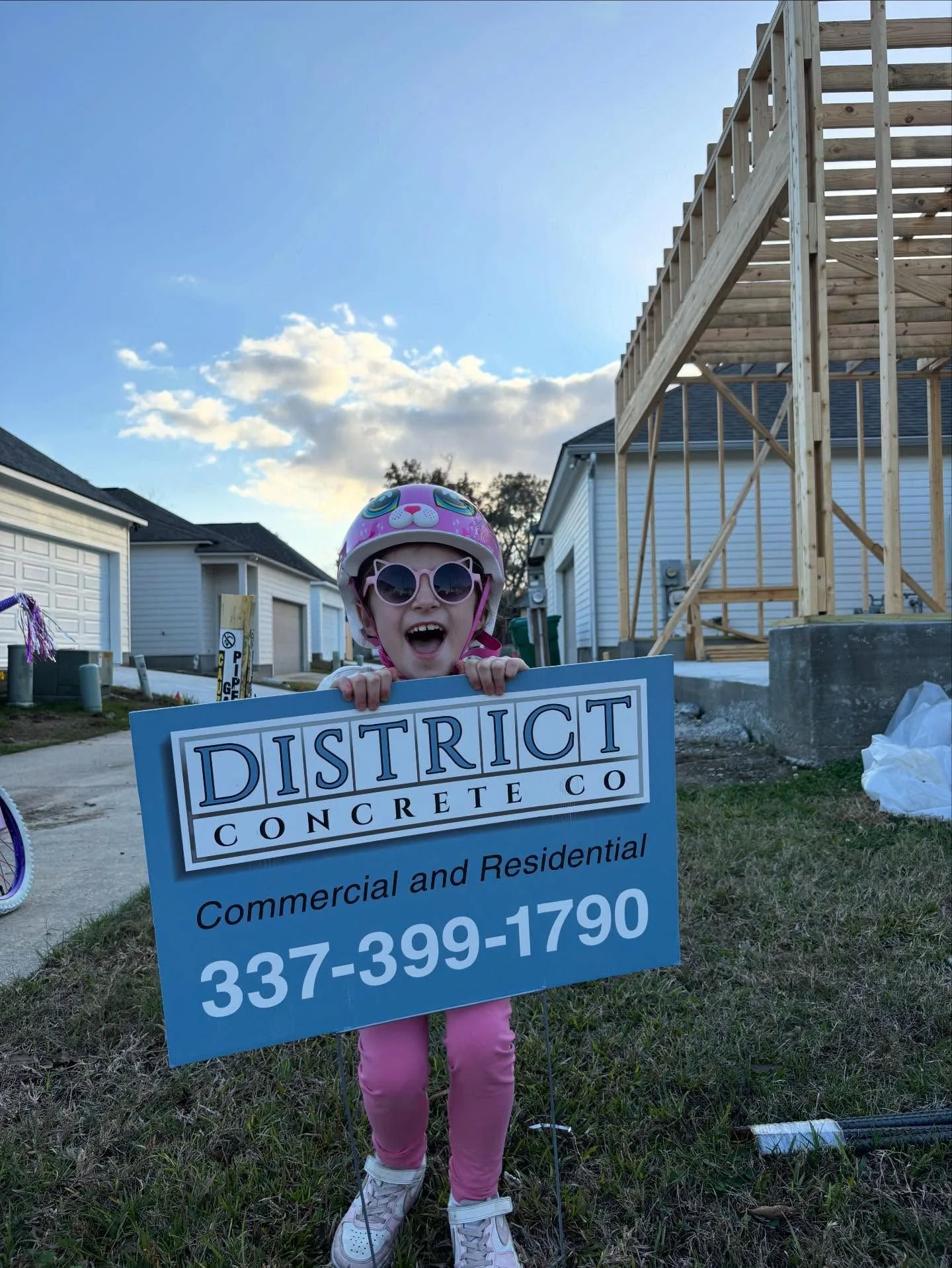 girl holding up district concrete sign